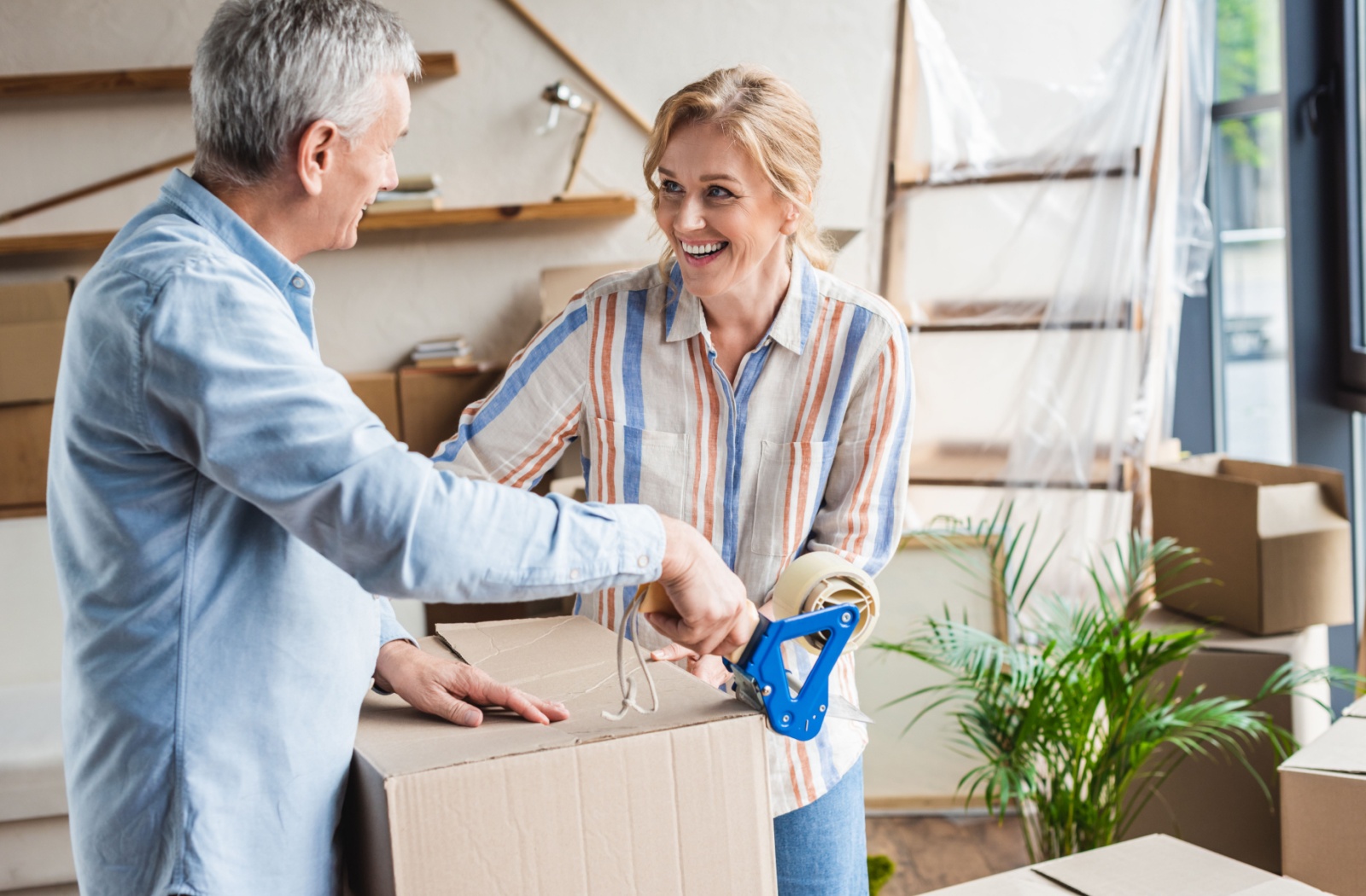 A young woman helps her elderly father pack his boxed as he prepares to move into assisted living.