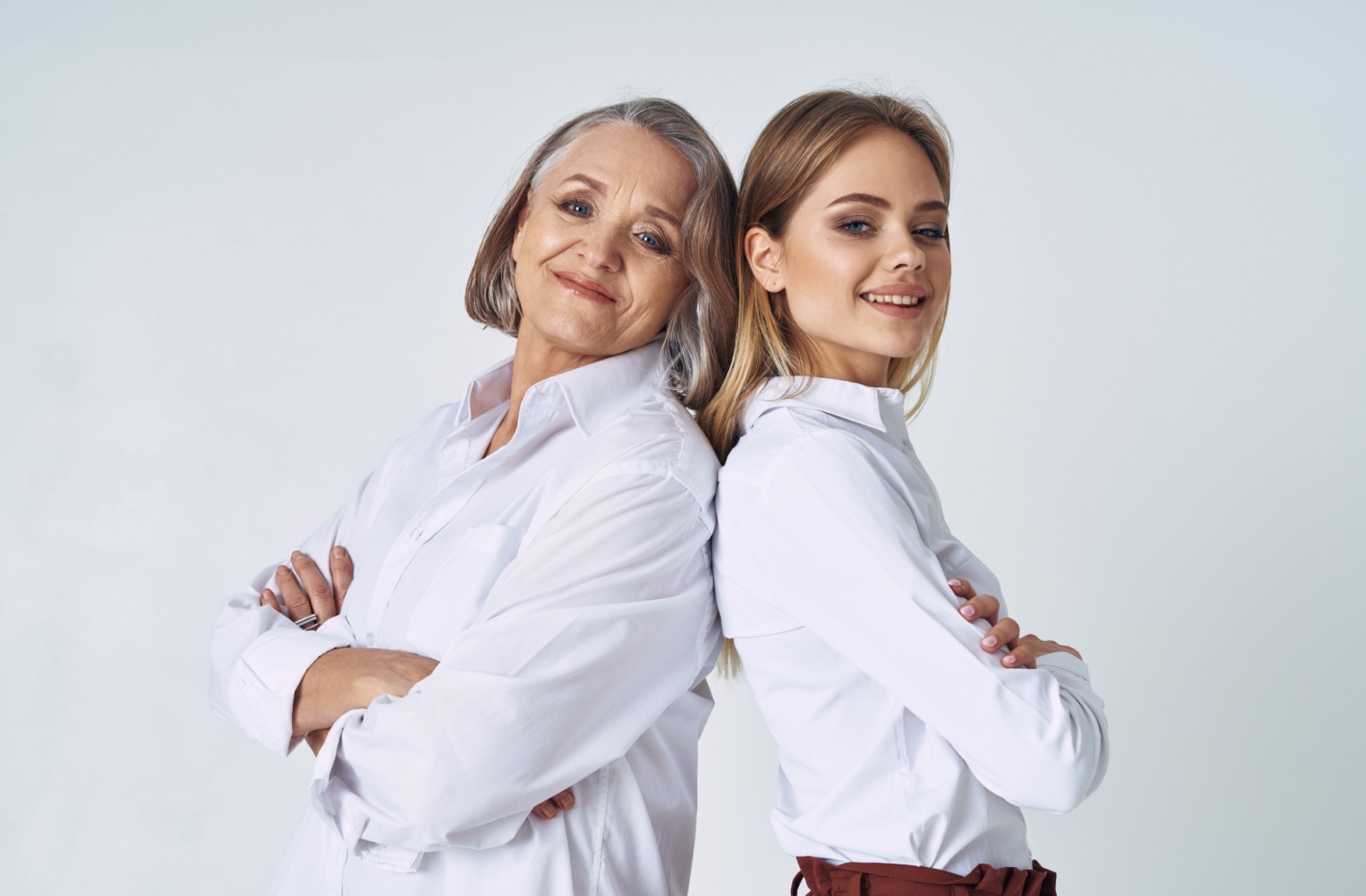 A young woman and her mother stand back to back as they look into the camera