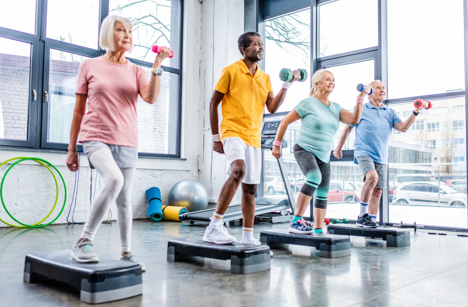 A group of seniors in the gym performing light exercise together.
