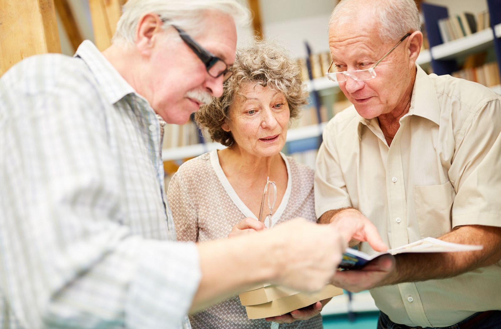 A group of seniors reading through a book together at a library.